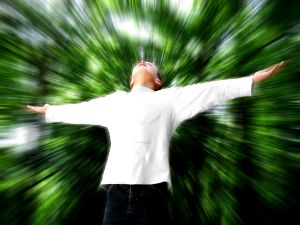 A person standing with arms outstretched against a green, motion-blurred background